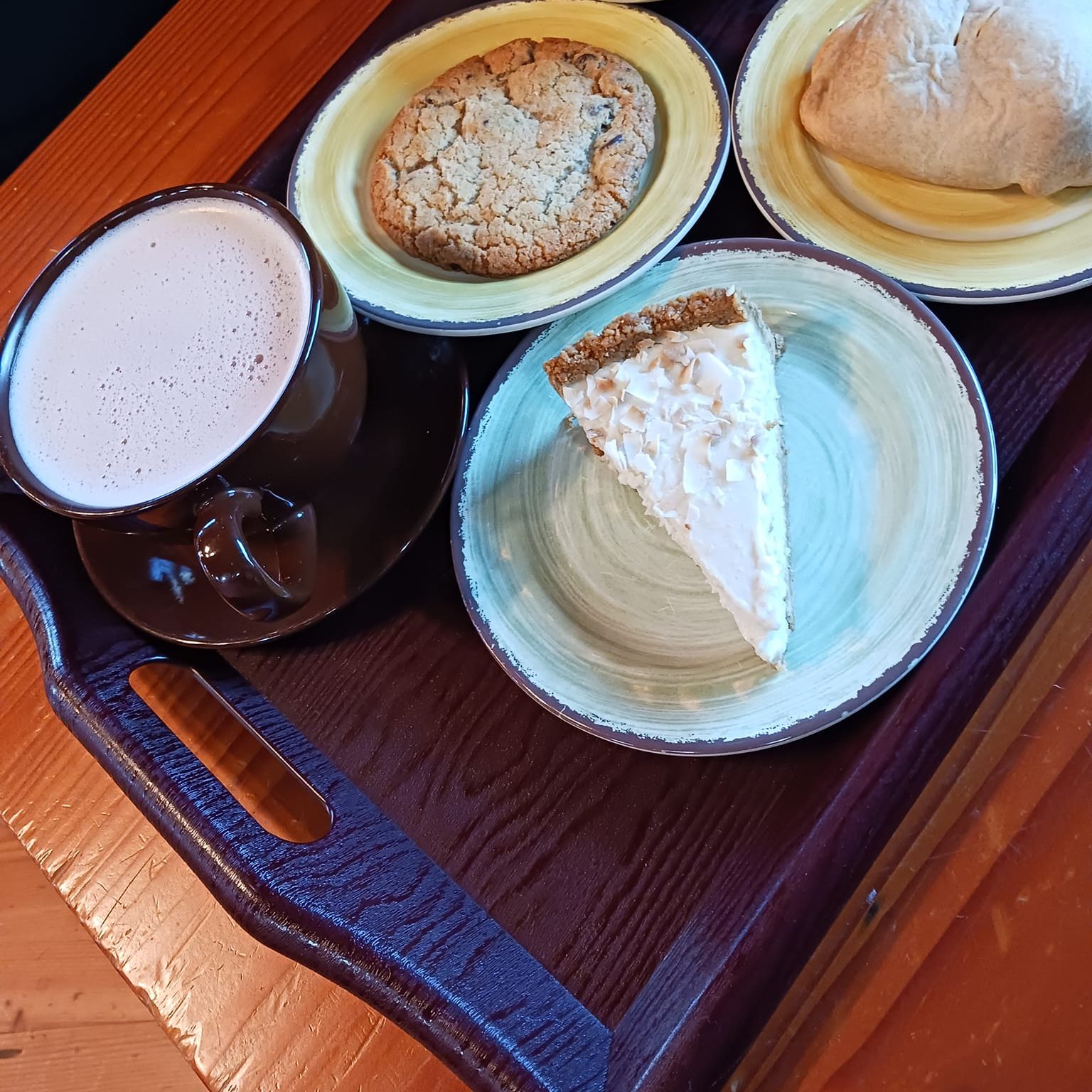 slices of pie, a hand pie and a latte on a tray