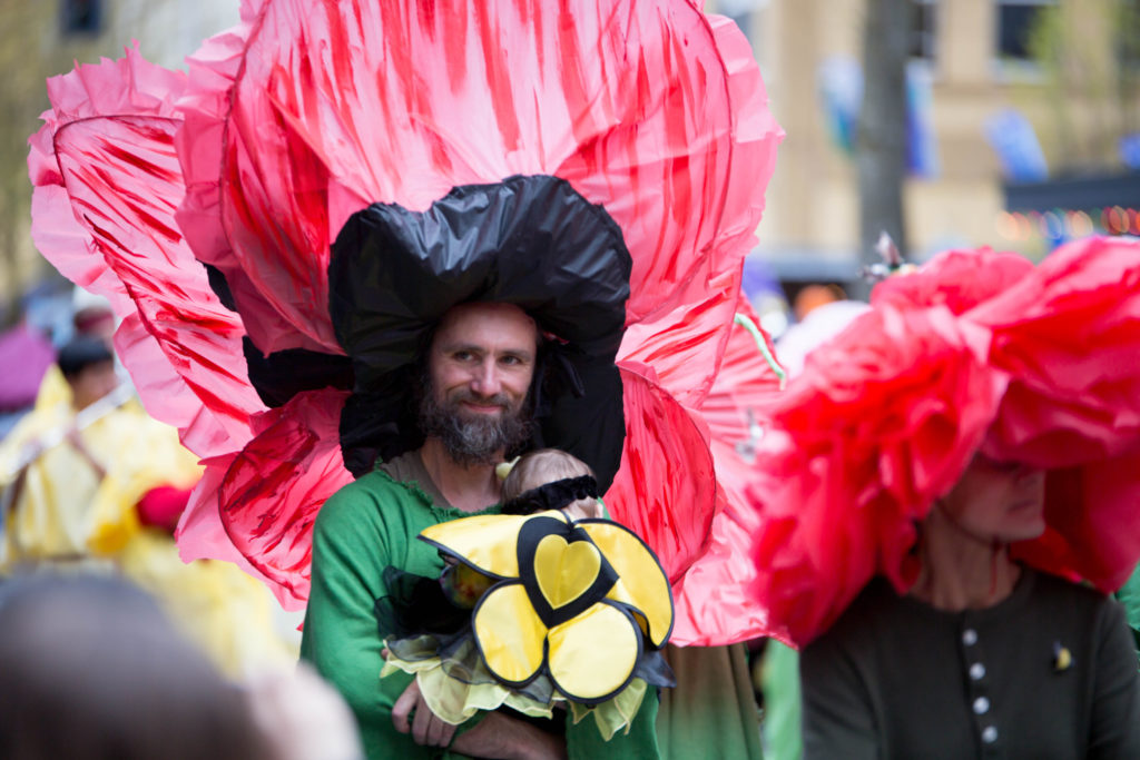 person dressed as a large red flower for Olympia's Procession of the species