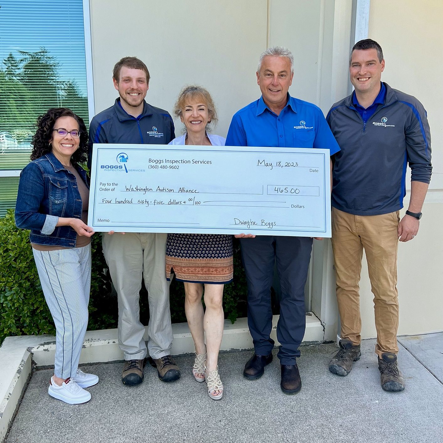 five people hold up a large check