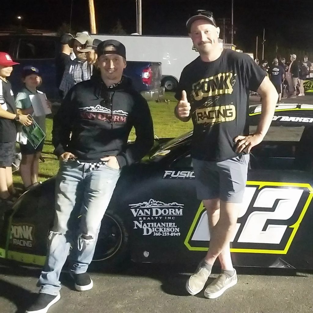 Nathaniel Dickison standing with a man giving the thumbs up. Both are leaning on a racecar with the number "22" and a sticker that says 'Van Dorm Realty Inc" Nathaniel Dickison 360.259.8949"