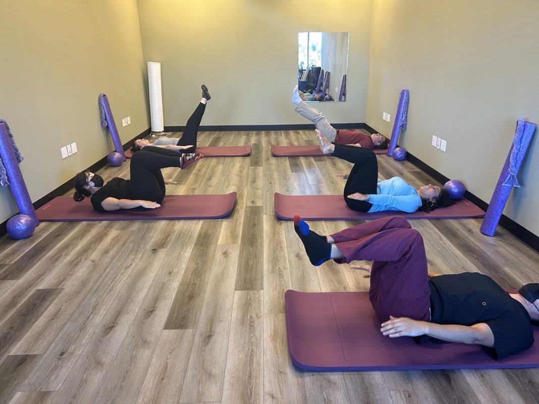 people doing pilates on yoga mats - lying on their backs with legs up in the air at right angles - at Penrose Physical Therapy