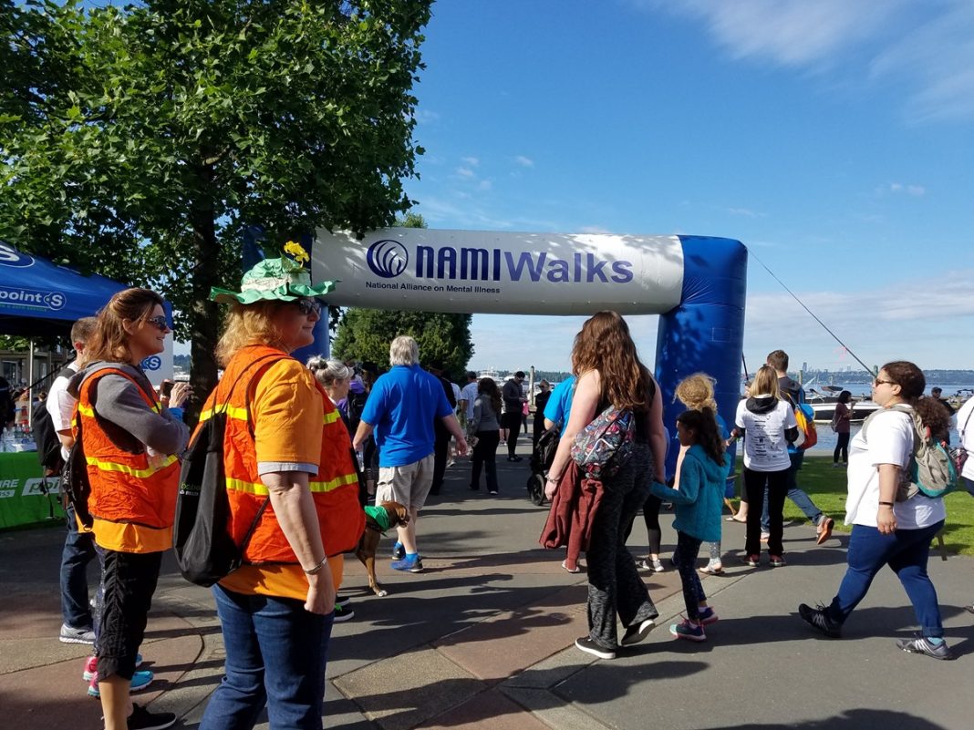 large group of people walking on a roadside with a large inflatable arch in the background