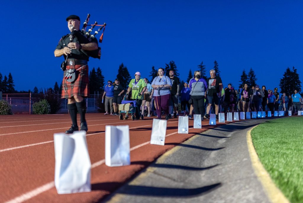 people running on a track with paper luminarias along it