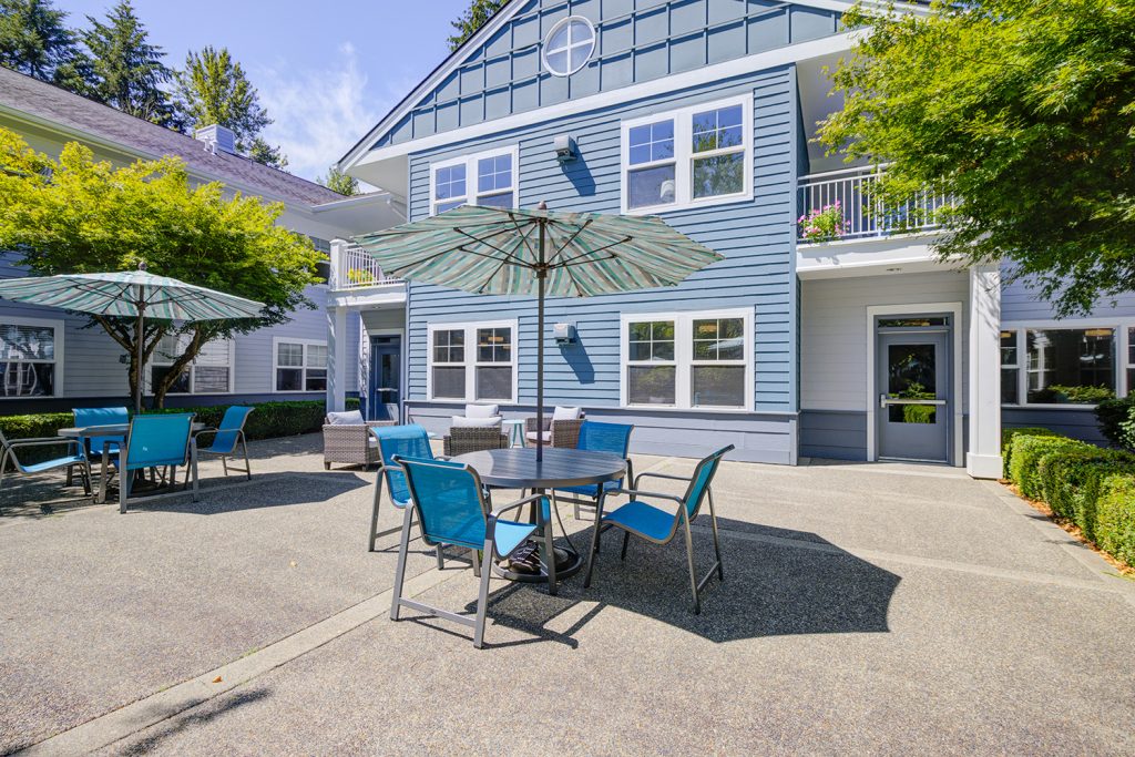 a patio outside Sequoia Senior Living with table with an umbrella and four chairs