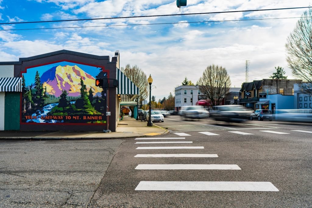 downtown Yelm cross roads with a mural on the side of a building depicting Mount Rainier with the words, 'Yelm - Gateway to Mt. Rainier.'