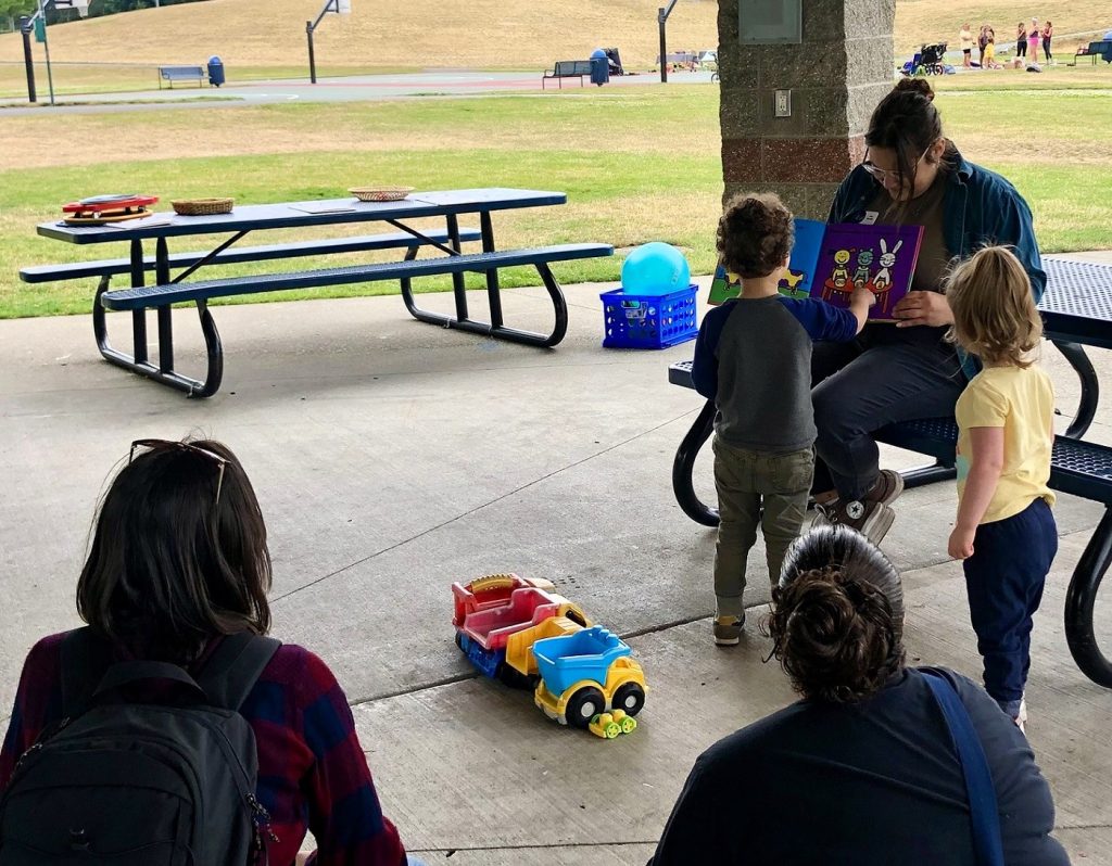 adults with kids under a shelter at a park