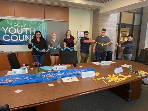 A row of high school students posing for a photo with paper chains and a banner that says Lacey Youth Council
