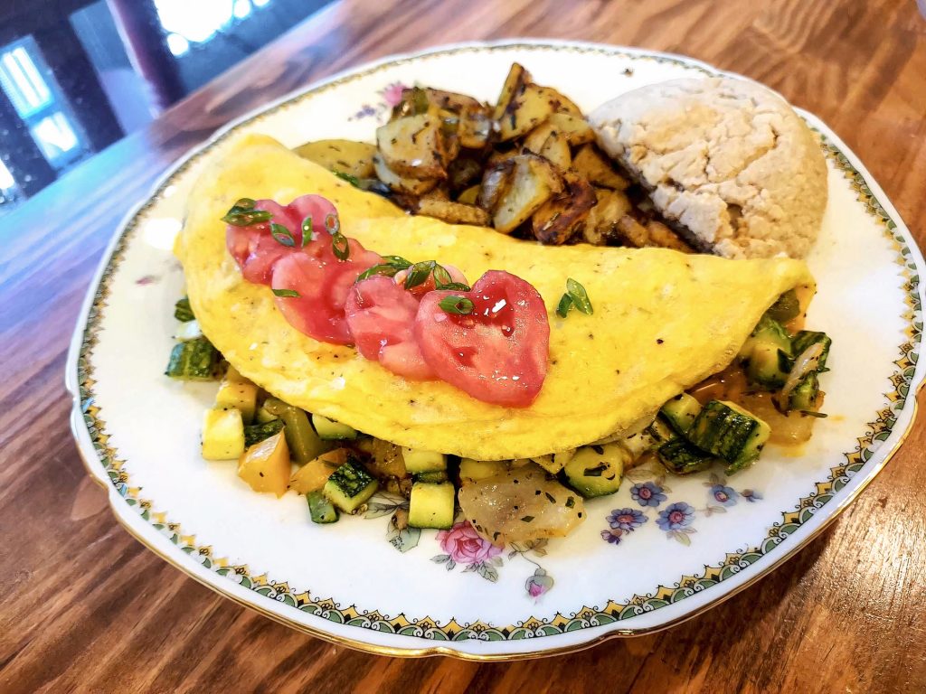 an huge egg omelet with sliced tomatoes on top and a biscuit and vegetables on the side at The Marie Bed & Breakfast in Olympia