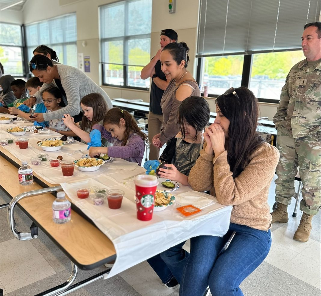 families sitting at a table eating with military men in fatigues