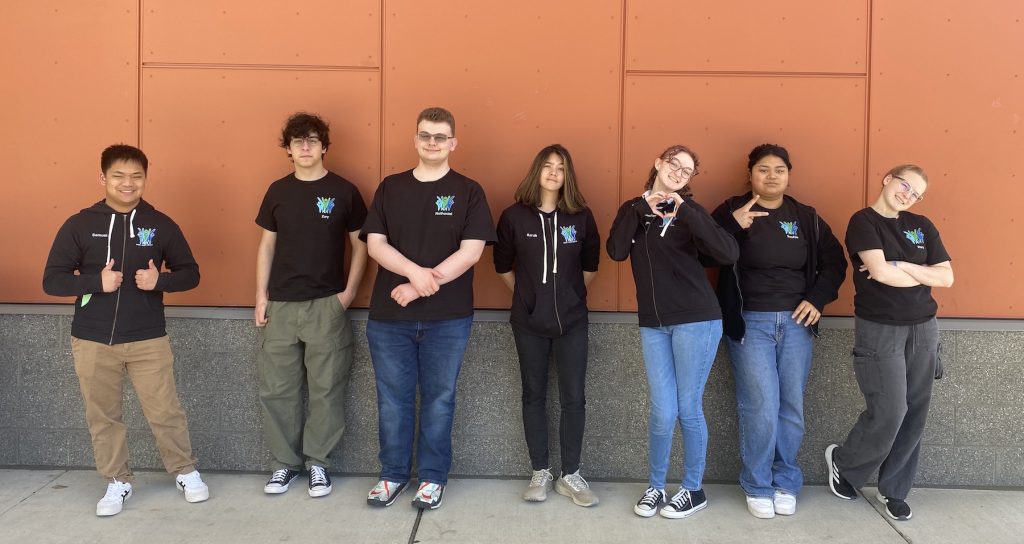 A row of high school students posing for a photo with matching sweatshirts on