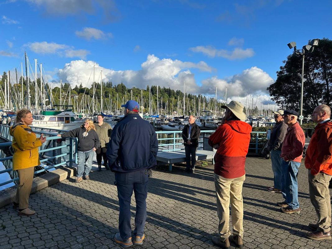 people standing and listen to someone talk at an overlook at the Port of Olympia