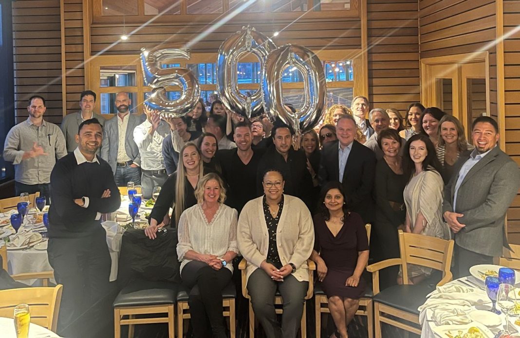 group of people posing for a photo with number balloons that read '500"