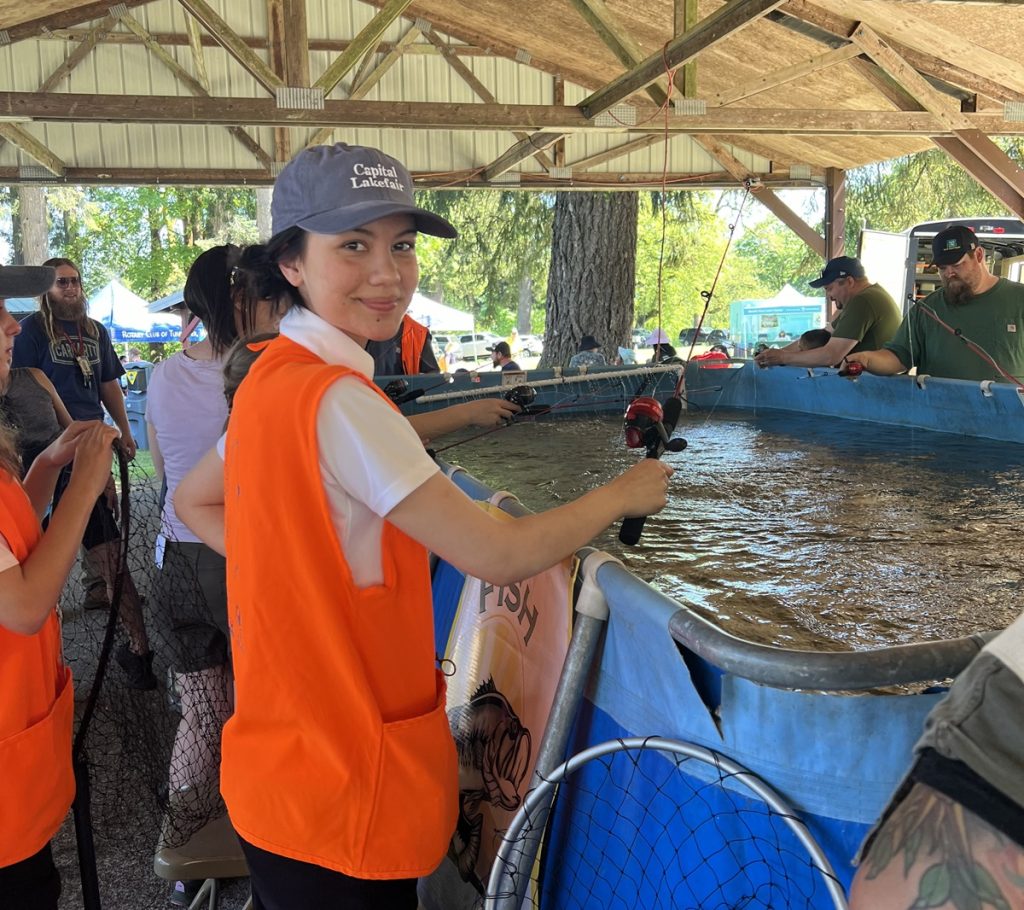young adult wearing an orange vest fishing out an above ground pool at Capital Lakefair