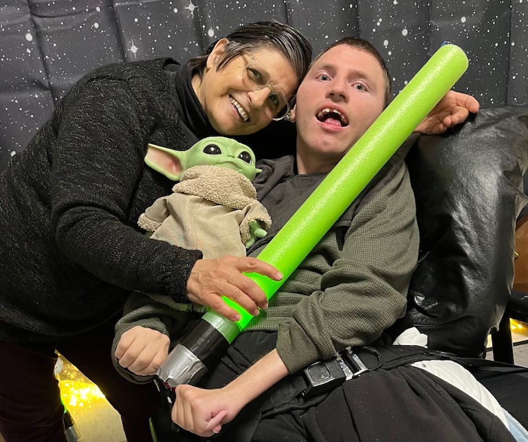 two people hugging each other with a lightsaber and Grogu