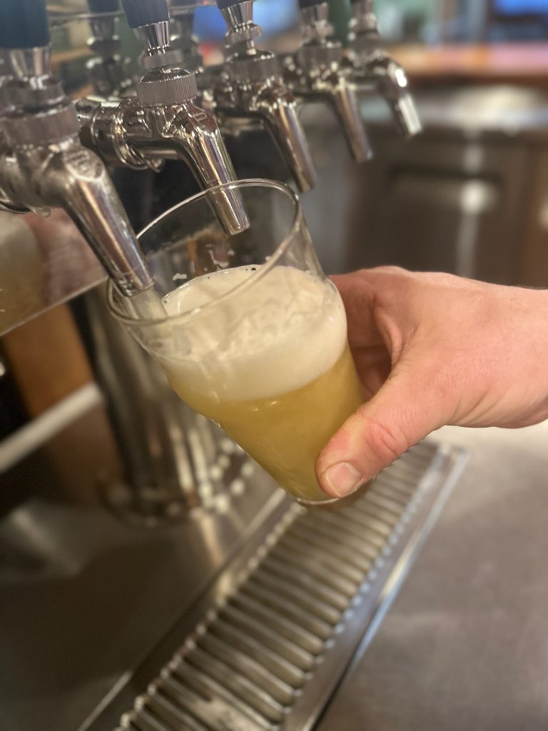 a hand put beer in a glass via a tap