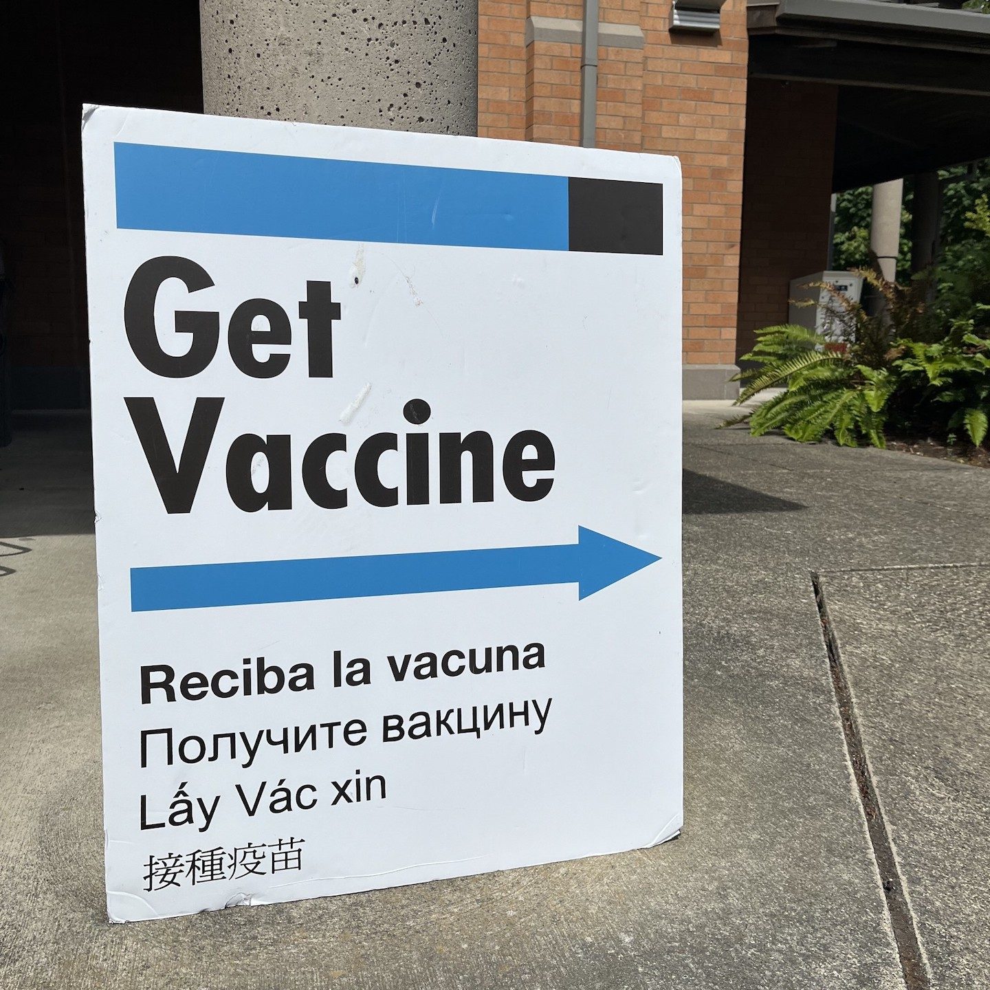 white sign with a blue arrow and wording that says 'Get Vaccine'