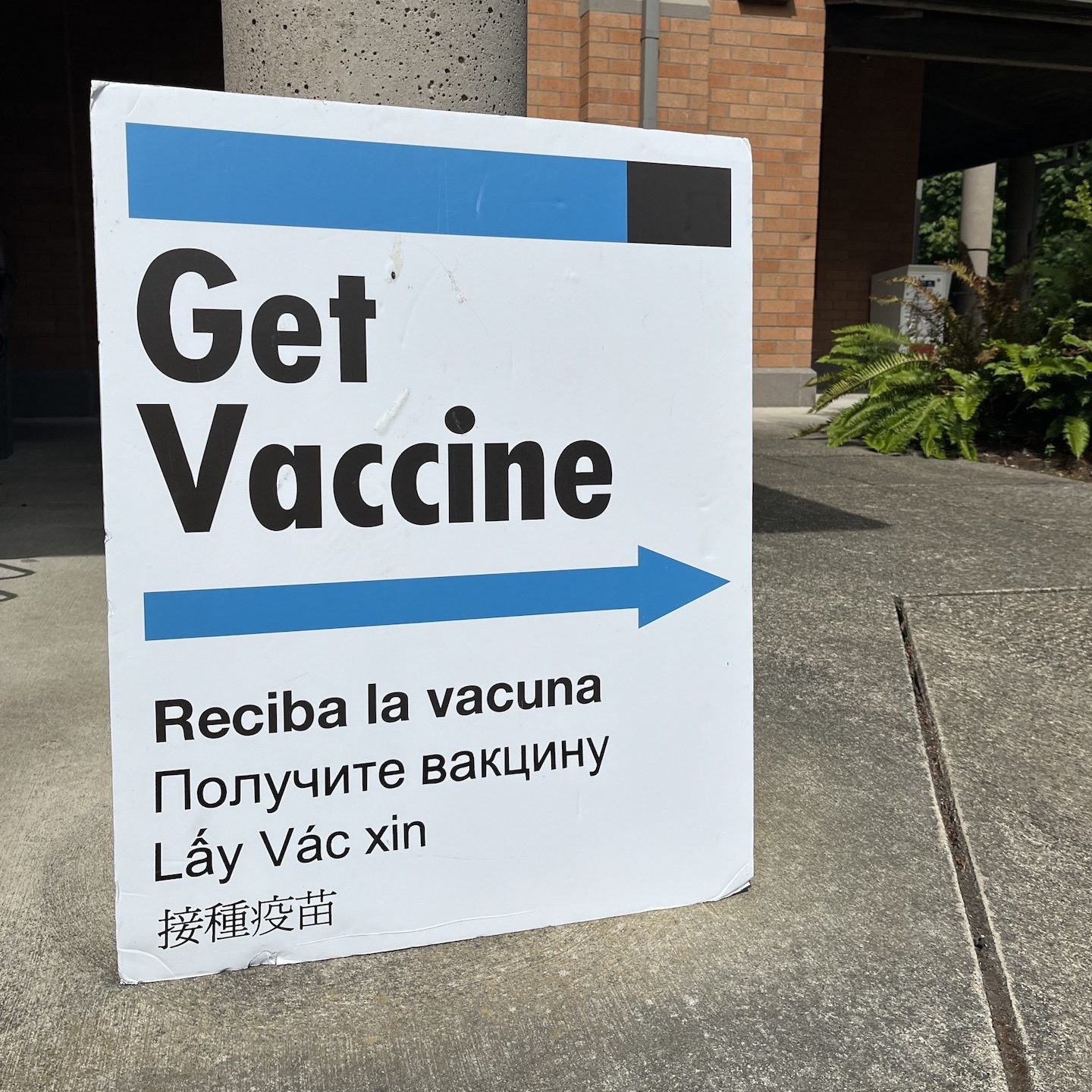 white sign with a blue arrow and wording that says 'Get Vaccine'