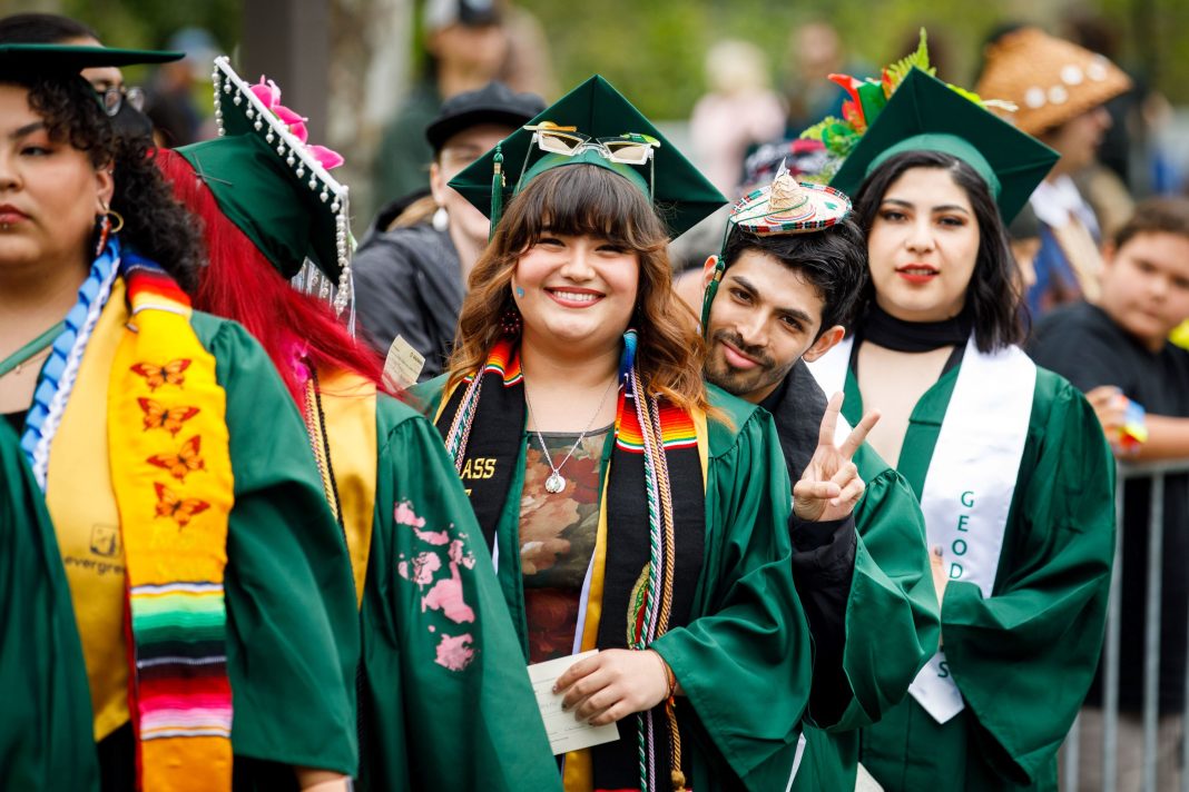 The Evergreen State College graduates in green caps and gowns with colorful accessories