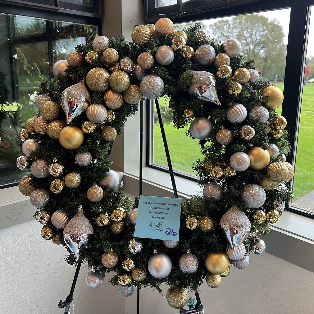 large holiday wreath with gold and silver balls on a stand
