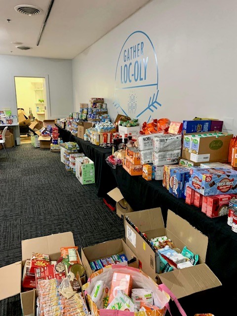 boxes and bags of food on tables and on the ground