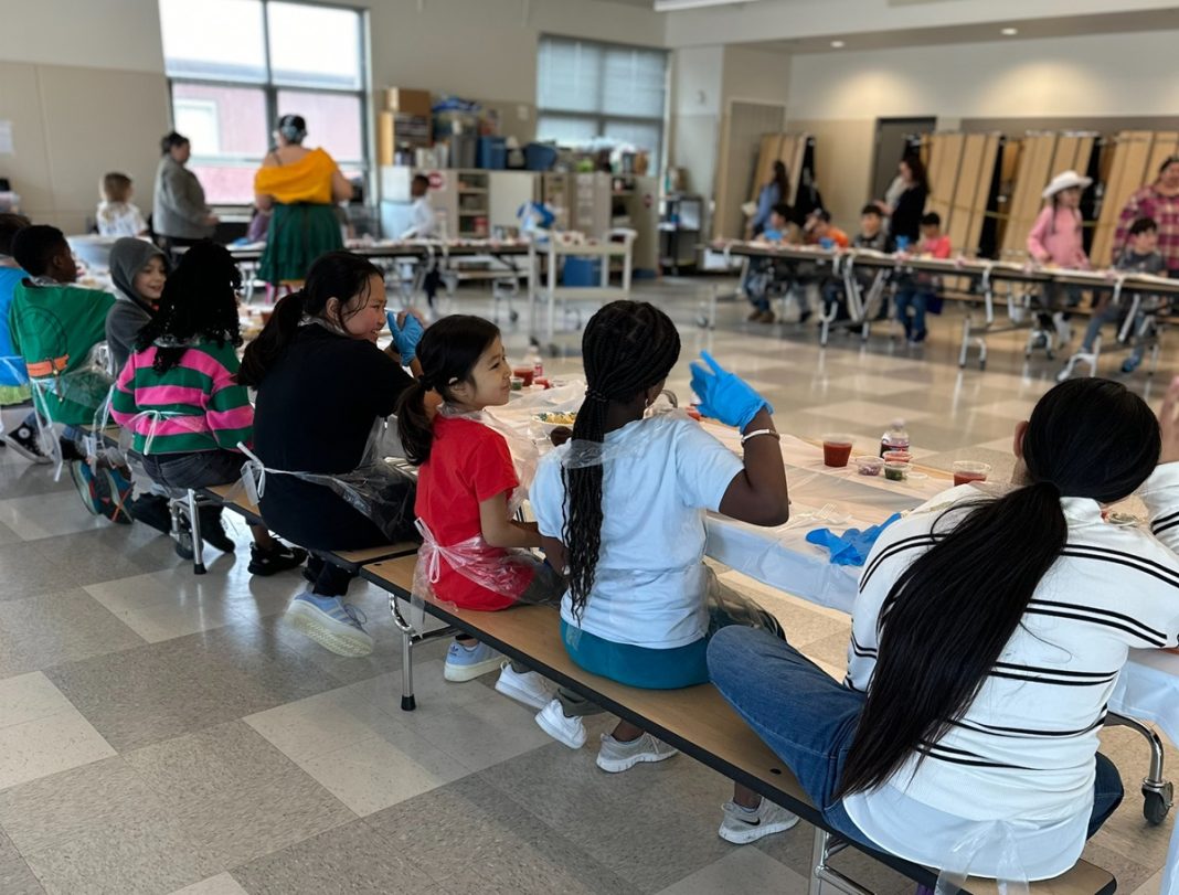 kids sitting at long tables together eating