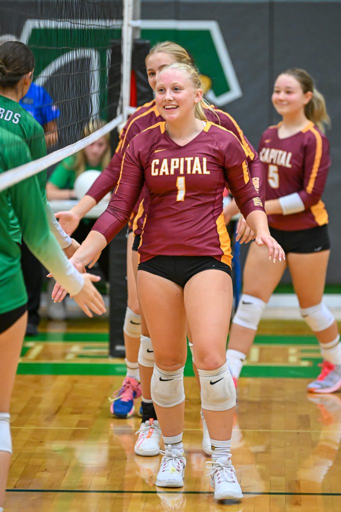 girls high fiving under a volleyball net