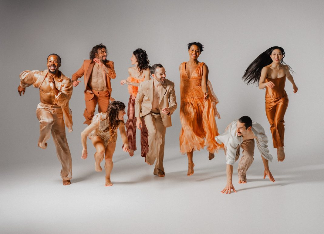 group of people dancing against a white backdrop