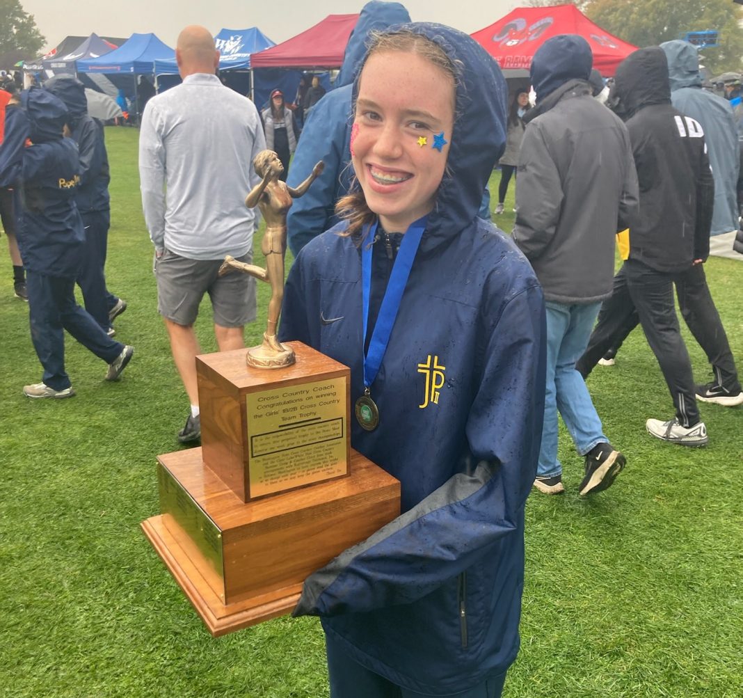 high school cross country girl holding a large trophy