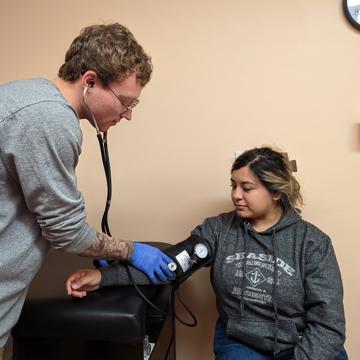 a doctor checks a woman's blood pressure while she is sitting