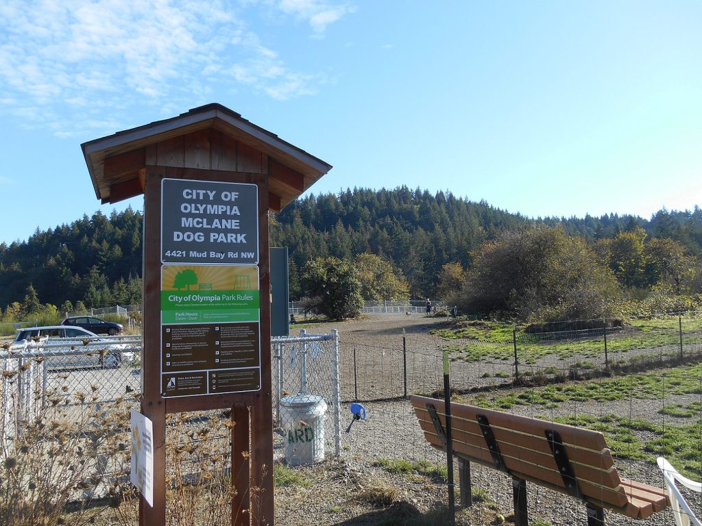 a field with cross fencing and a wooden sign that says McLane Dog Park