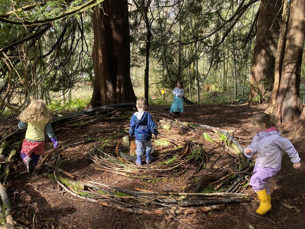 kids playing with sticks in a circle pattern in a woods