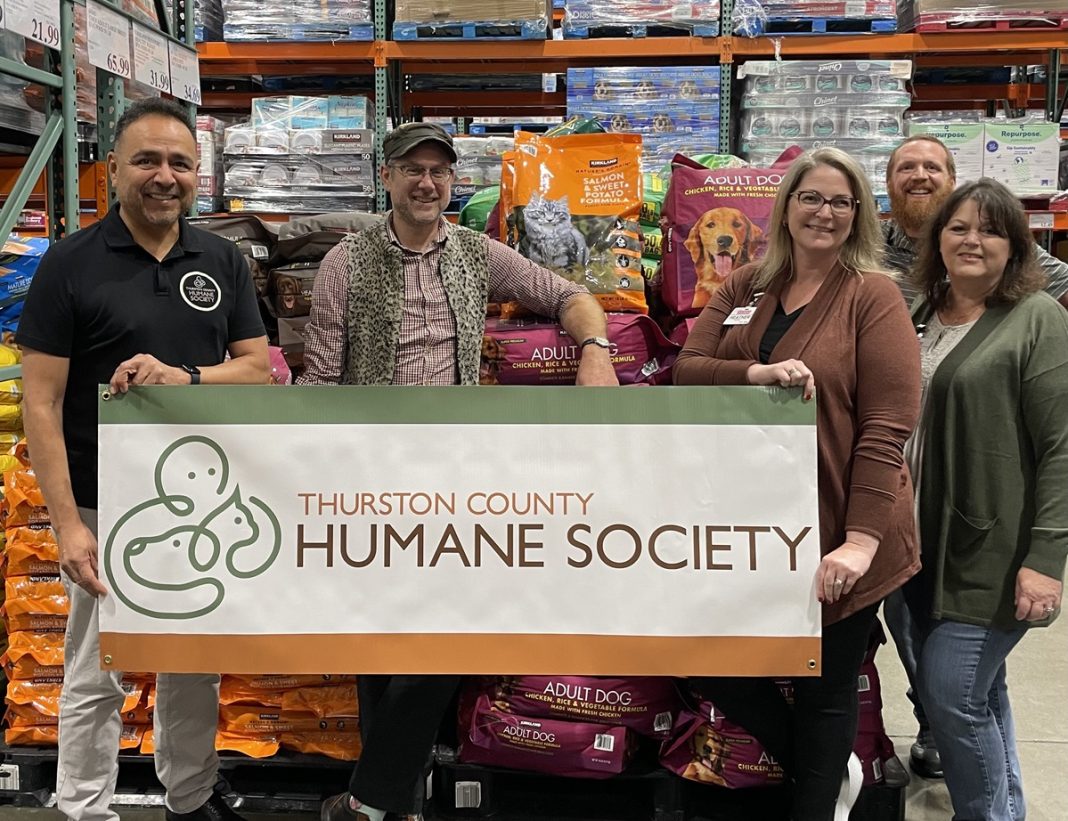 a group of people in front of a pallet of dog food at Costco. They are hold a 'Thurston County Humane Society' banner
