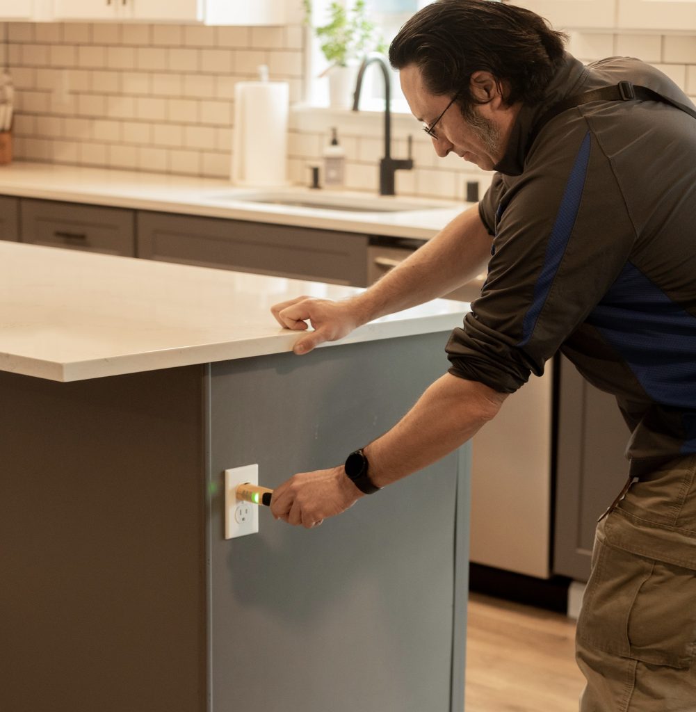 Boggs Inspection Services tech screwing a plate cover on an outlet of a kitchen island