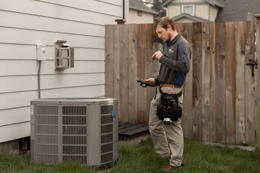 Boggs Inspection Services tech inspecting an HVAC system outside a home