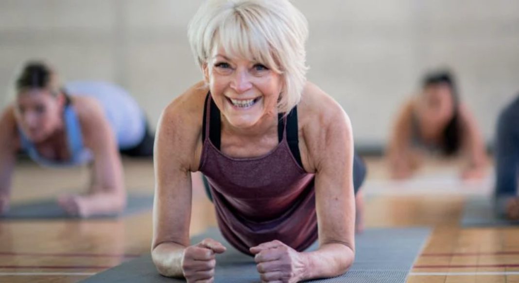 a senior woman doing a plank on a yoga mat