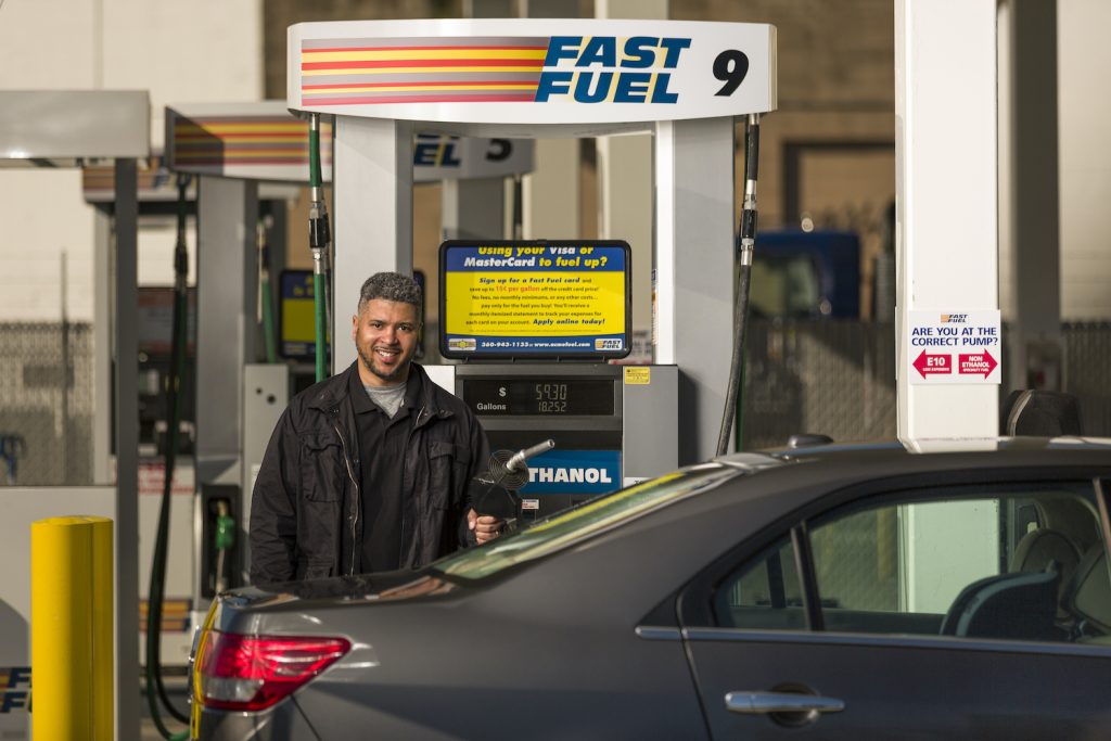 man fueling his grey car at a Fast Fuel Station