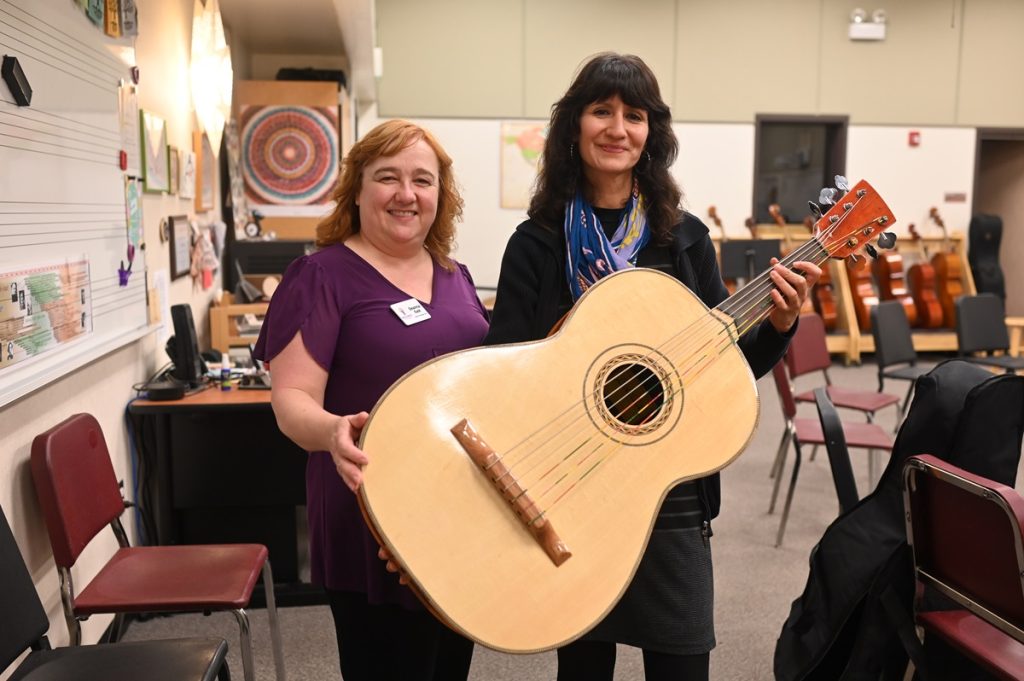 two women pose holding a guitarron