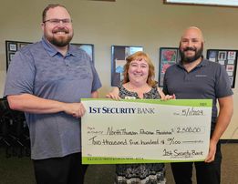 Three people holding a large check