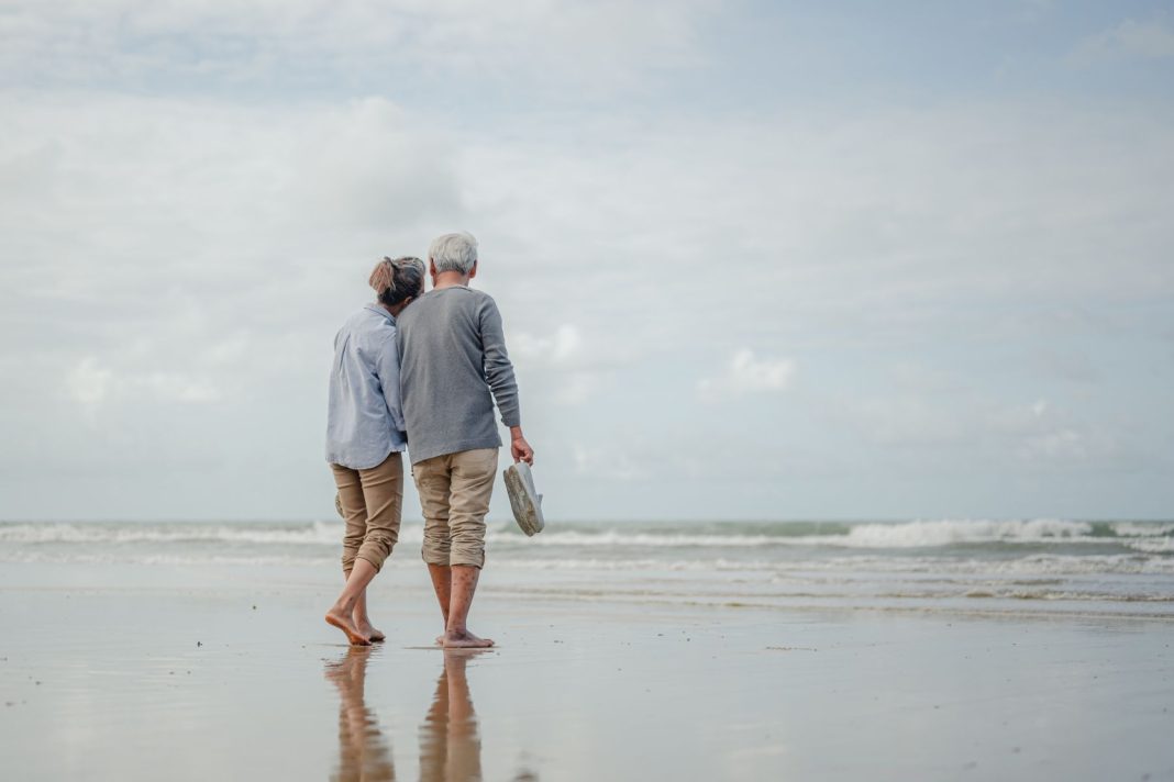 a man and a woman walk hand in hand along the shoreline