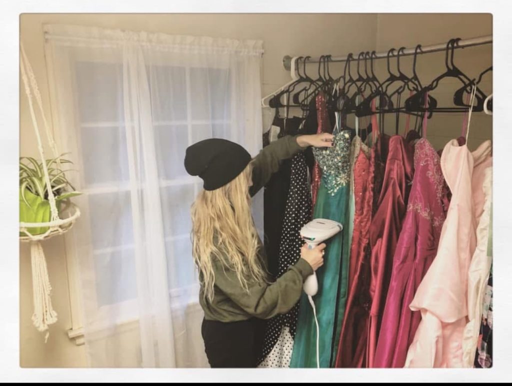 Sabrina White steaming a rack of formal dresses
