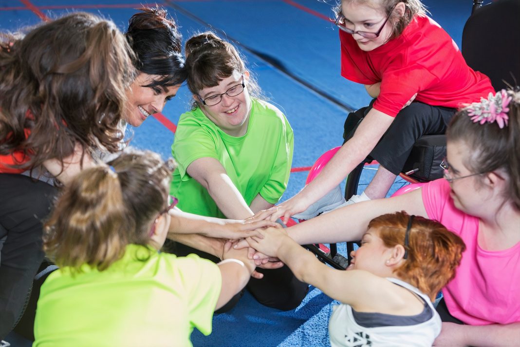 kids in a circle with arms stretched out inside the circle and their hands stacked on top of each other