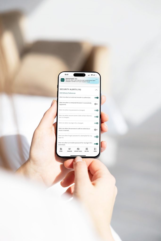 a person holding a phone with OlyFed's app on it