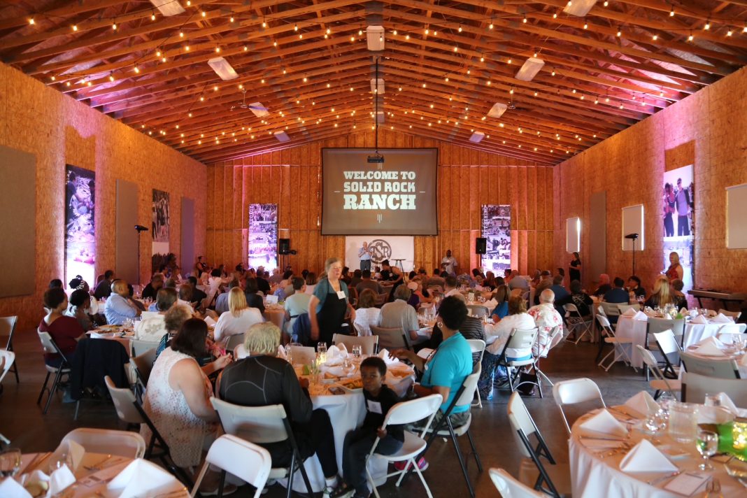 a large group of people sitting at round tables in a big building