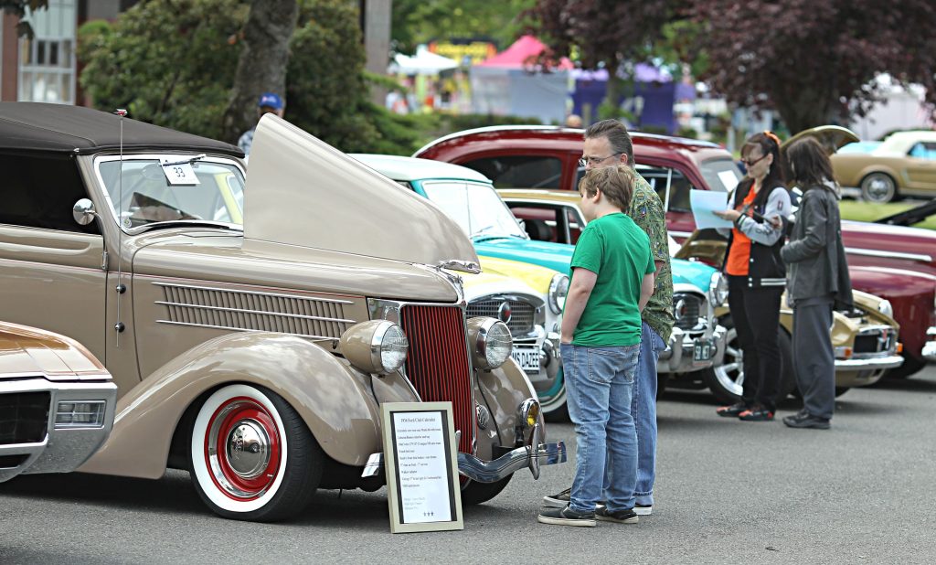 classic cars on a street with people looking at them