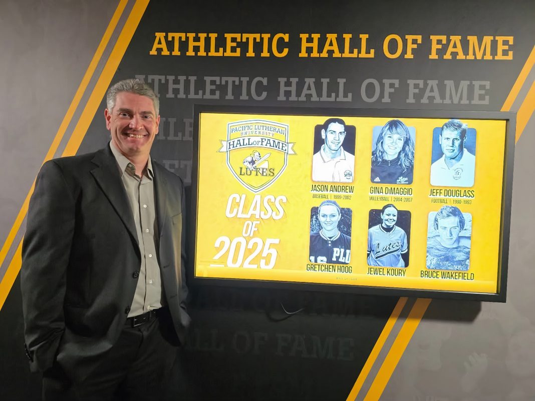 Jason Andrew in a suit standing next to a wall that says Athletic Hall of Fame with a big screen on it with photos of the 2025 hall of fame inductees on it with their names underneath: Jason Andrew, athlete, Gina Dimaggio, Jeff Douglass, Gretchen Hoog (ruecker), Jewel Koury, Bruce Wakefield, and the . Class of 2025. A logo in the top left says Pacific Lutheran University, Hall of Fame, Lutes