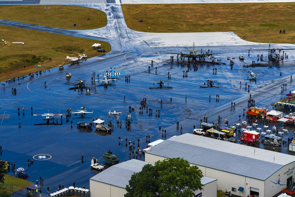 aerial photo of the Port of Olympia's runway with vintage airplans on it and people milling around - food trucks are off to the side