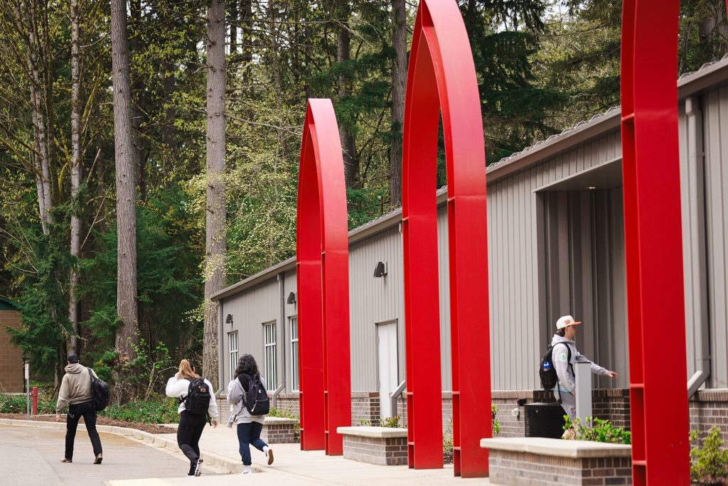 Commencement profile photos for the program Students walking around campus near Ernsdorff arches.
