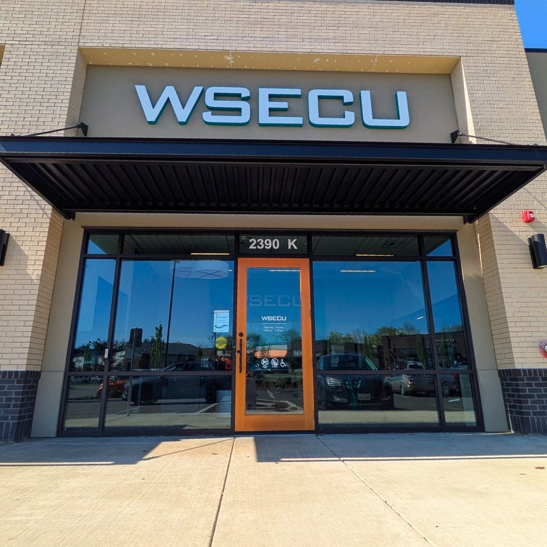 Exterior of the WSECU Hawks Prairie branch with a wood door, awning and "WSECU" lettering above it in light blue