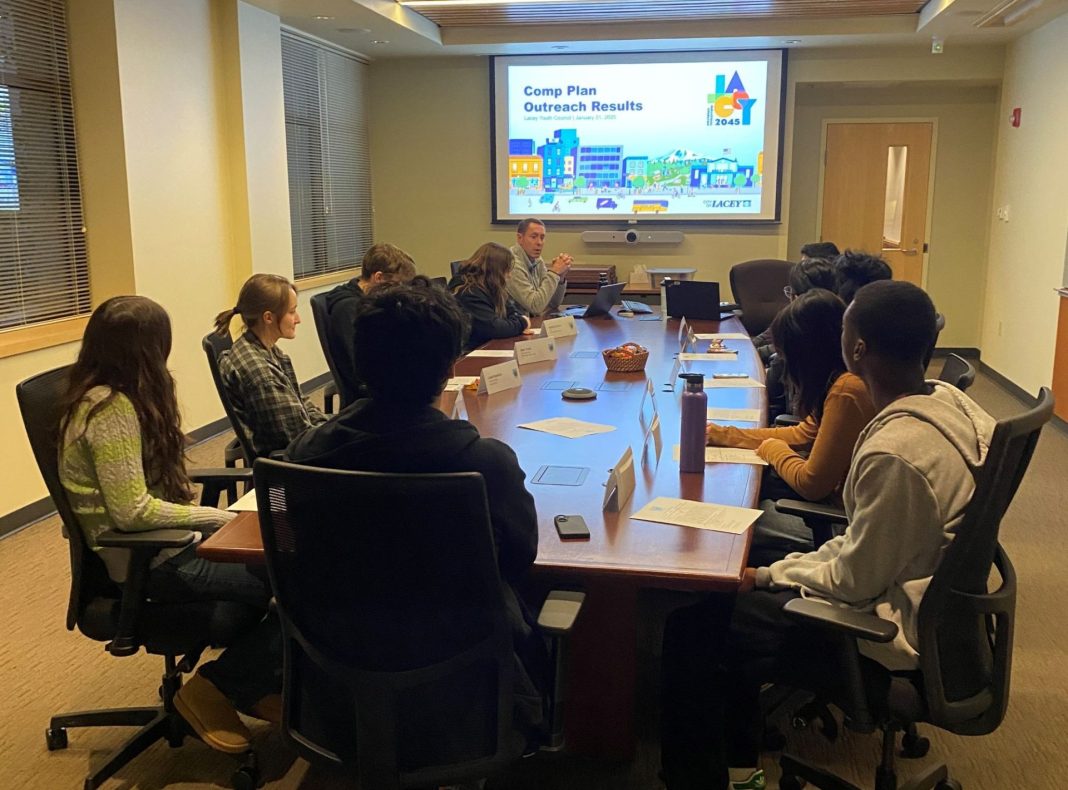Lacey Youth Council sitting in a meting room at a long table, a projection on the wall shows a city drawing and the works "Comp Plan Outreach Results"