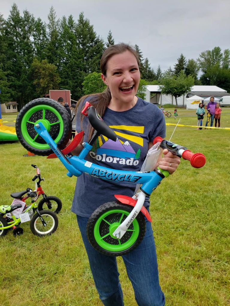 a teenage girl holds up a kids bicycle that will be given away at the Lacey Duck Dash